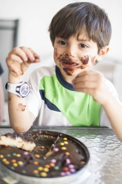 Kahverengi suratlı, çikolata yiyen bir çocuk.