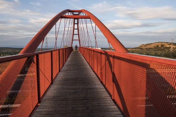 elevated red bridge over the highway with anonymous cyclist traveling