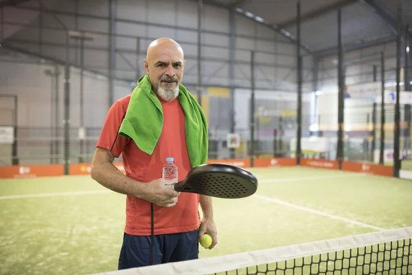 Зрілий чоловік в тенісному корті з рушником і пляшкою води . — стокове фото