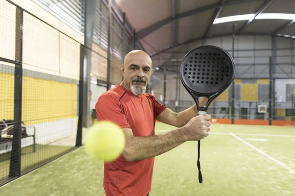 Homem sênior jogando paddle tênis backhand no tribunal — Fotografia de Stock