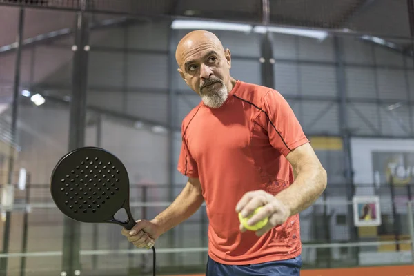 Homem sênior jogando paddle tênis no tribunal — Fotografia de Stock