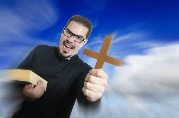 Priest on blue cloudy sky showing cross with anger and zoom effect
