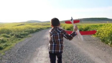 Oyuncak uçağı olan küçük çocuk bahar tarlasında oynuyor.