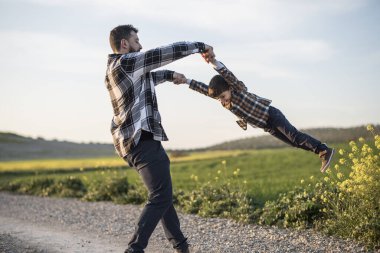 Dönen baba oğlunu kollarıyla kavrıyor, dönüyor ve oynuyor.