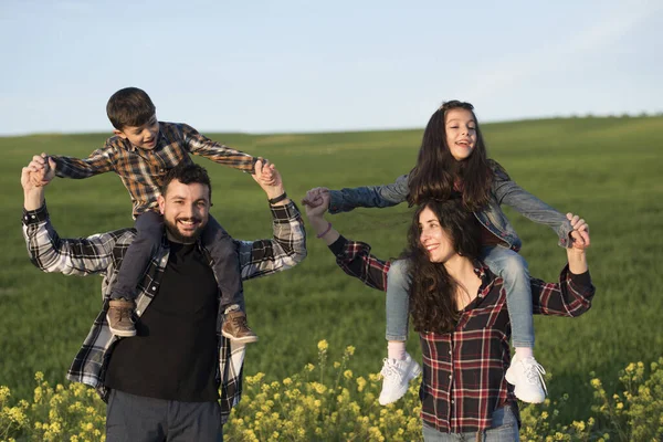 Vier Glückliche Familienmitglieder Spielende Kinder Auf Den Schultern Der Eltern — Stockfoto