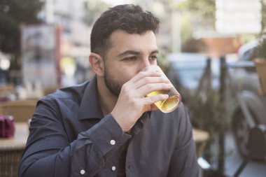 Yetişkin bir adam bar terasında bira içiyor.