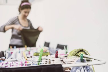 Endülüs 'lü kadın ev hanımı çamaşır ipine beyaz arka plan duvarlı giysiler asıyor.