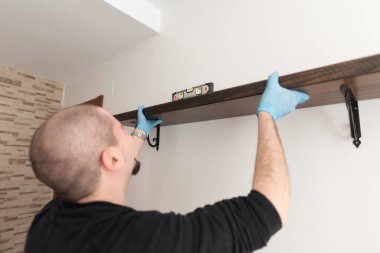 Ruh seviyesine sahip bir adam evdeki kitaplığın yerini hazırlar.