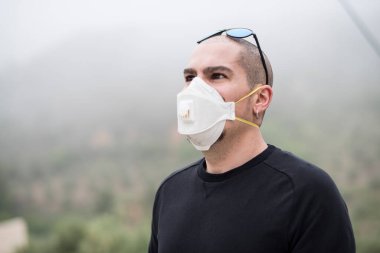 Kirlenmeyi, alerjiyi ya da virüsü önlemek için ormanda maske takan bir adam.