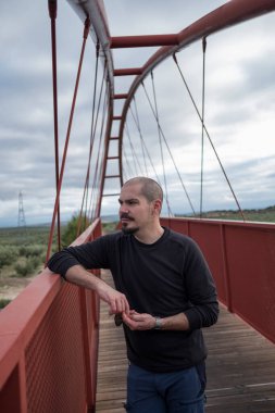 Bulutlu bir günde köprüde kel havalı bir adam portresi