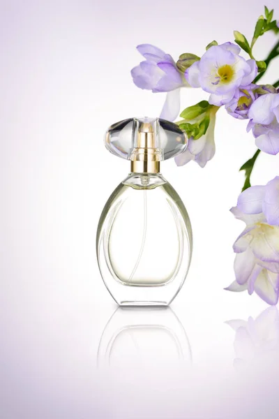 Bottiglia di profumo con fiori viola — Foto Stock