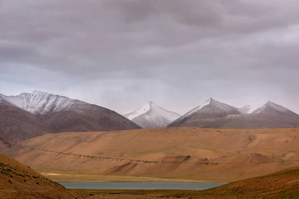 Paesaggio Ladakh con montagne innevate e un lungo filo di bandiere buddiste — Foto Stock