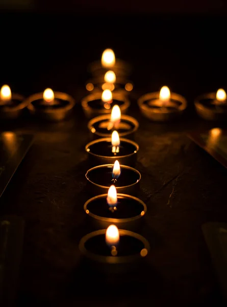 Many burning candles laid out in the form of a cross. Selective focus. Sorrow, tragedy, a symbol of memory.