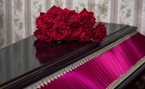 Kırmızı güllerle süslenmiş ahşap kapalı tabut. Merhumun defin töreni..