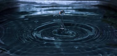 Bir damla su düşer ve bir sıçrama yaratır. Seçici odak.