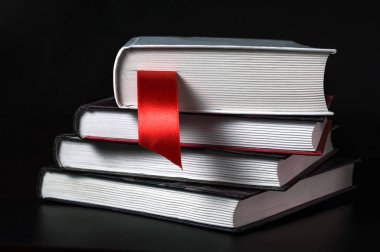 Siyah arka planda kitap ayracı olan bir yığın kitap. Okuma, eğitim.