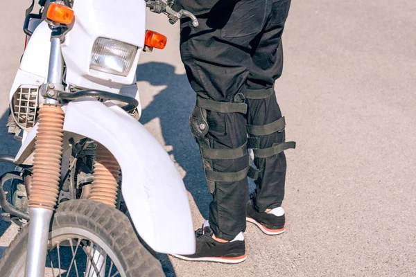 摩托车旁边那个人的脚靠得很近 摩托车手的弹药和特殊服装 摩托车手专用护膝护膝装置 — 图库照片