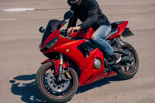 A man rides a red motorcycle in the afternoon . Lessons in motorcycle school.  Bike driving courses for adults. Man learn to drive a bike. Improve driving skills on the training ground