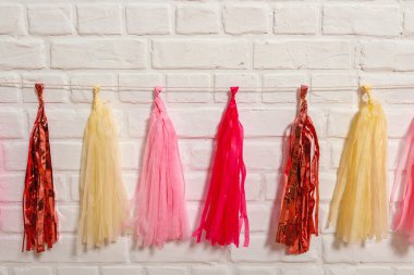 Beyaz tuğla duvarda pembe folyo kağıt bir çelenk. Doğum günü için kağıt süslemeleri. Tatil festivali için fotoğraf kabini dekorasyonu için aksesuarlar..