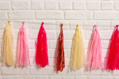 Beyaz tuğla duvarda pembe folyo kağıt bir çelenk. Doğum günü için kağıt süslemeleri. Tatil festivali için fotoğraf kabini dekorasyonu için aksesuarlar..