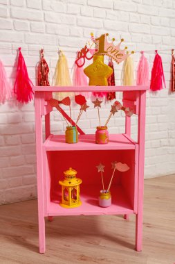 Küçük kız için ilk doğum günü partisi için pembe stil dekorasyonu. Beyaz tuğla bir duvarda kağıt çelenkler ve fotoğraf kabini dekorları. Şık aksesuarlar Bir yıllık fotoğraf çekimi