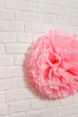 Beyaz tuğla duvarda pembe mendil çiçeği. Doğum günü için kağıt süslemeleri. Tatil festivali için fotoğraf kabini dekorasyonu için aksesuarlar..