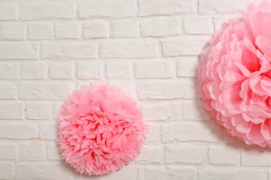 Beyaz tuğla duvarda pembe mendil çiçeği. Doğum günü için kağıt süslemeleri. Tatil festivali için fotoğraf kabini dekorasyonu için aksesuarlar..