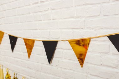 Beyaz bir duvarda altın renkli siyah çelenkler. İpte kağıt folyo bayrakları. Kağıt çelenk mutlu yıllar düğün dekorasyonu. Matte ve parlak altın renkli çelenk parti dekorasyonu için.