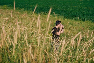 Sahada küçük aynasız kamerası olan bir adam. Bir adam doğadaki manzaraları fotoğraflıyor. Kameralı genç adam.