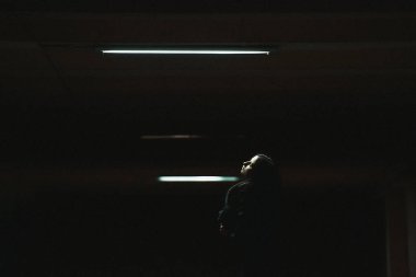 Gece şehrinde uzun siyah saçlı, siyah elbiseli bir kızın portresi. Karanlık bir otoparktaki kız. Şehirde karanlık bir anahtarın portresi