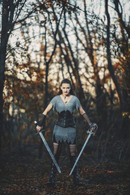 Metal kılıçlı gotik tarzda zırhlı kız şövalye. Kadın savaşçı Amazon Cadılar Bayramı için orman imajında.