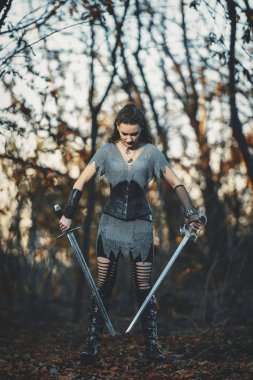 Metal kılıçlı gotik tarzda zırhlı kız şövalye. Kadın savaşçı Amazon Cadılar Bayramı için orman imajında.