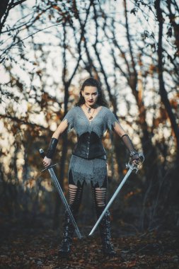 Metal kılıçlı gotik tarzda zırhlı kız şövalye. Kadın savaşçı Amazon Cadılar Bayramı için orman imajında.