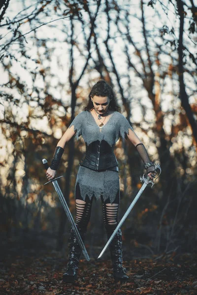 Metal kılıçlı gotik tarzda zırhlı kız şövalye. Kadın savaşçı Amazon Cadılar Bayramı için orman imajında.