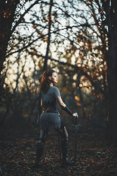 チェーンメールの少女騎士は ゴシック様式の金属剣コスプレをしています 女性戦士アマゾンの森のイメージのハロウィーン — ストック写真
