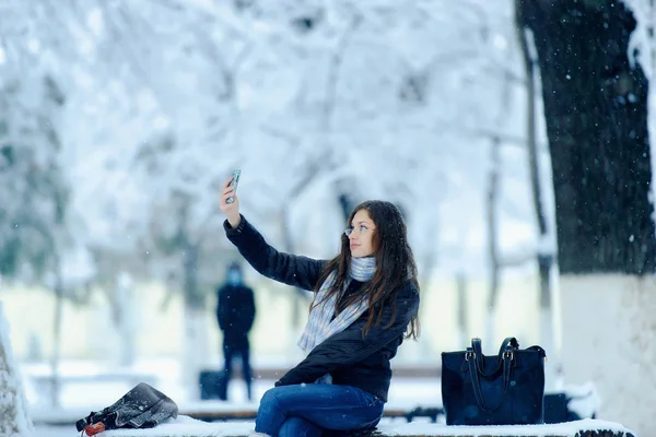 Girls winter outdoor in a snow-covered city. Romantic girl in glasses for vision on the street in winter under the snow. Beautiful young brunette woman in winter landscape