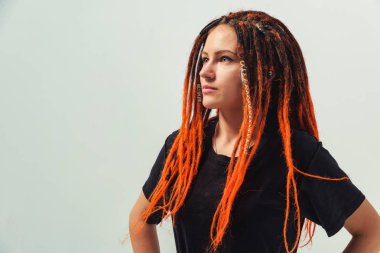 Beyaz arka planda kırmızı saçlı bir kız. Kafasında uzun kazayağı olan genç bir kadın. Turuncu rastalı gayri resmi kız.