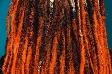 Dreadlocks turuncu kırmızı yakın plan. Saçlarını ören örgü ören saçlar. Ateşli kırmızı rastalı bir kız..