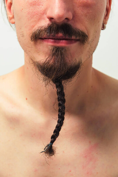 A man with a long beard braided pigtail close-up. Beard and moustache have adult men. Pigtail from beard