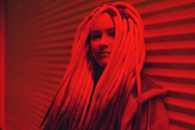 Kırmızı ışıkta siyah beyaz rastalı kız. Kırmızılı rastalı, gayri resmi görünümlü genç bir kadın. Kırmızı neonlu kıza uzun saplı.