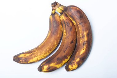 Kararmış muz kabuğu. Beyaz arka planda bir grup olgunlaşmış muz. Meyve ve muzun uygunsuz depolanması