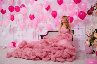 Balonların arka planında pembe balo elbisesi giyen genç bir kadın. Pembe ve beyaz balonlu Bulut elbisesi içinde güzel bir kız. Kızda havalı balo elbisesi var.