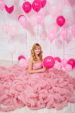 Balonların arka planında pembe balo elbisesi giyen genç bir kadın. Pembe ve beyaz balonlu Bulut elbisesi içinde güzel bir kız. Kızda havalı balo elbisesi var.