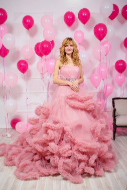Balonların arka planında pembe balo elbisesi giyen genç bir kadın. Pembe ve beyaz balonlu Bulut elbisesi içinde güzel bir kız. Kızda havalı balo elbisesi var.