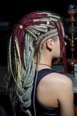 Renkli, yapay rastalı ve piercingli bir kız. Genç bir kadının kafasında beyaz ve Burgundy rastaları. Gayri resmi kültürden bir kızın görüntüsü.