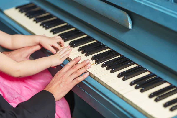 Men\'s and children\'s hands on the piano keys. Dad and little daughter play the piano. Hands on the black and white keys of a musical instrument