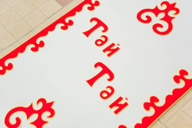 Kazak milli geleneği için bir çocuğun ipini kesmek. Kazaklar ve Kirghizlerin çocuk kutlama geleneğinin ilk adımları. Resimdeki başlık 