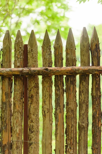 Wooden fence on the cottage. Fence with sharp peaks. Protective wooden structure from theft. Eco-friendly fence in the country