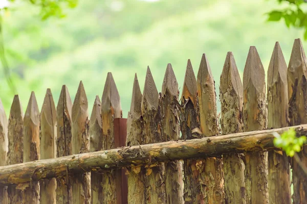 Wooden fence on the cottage. Fence with sharp peaks. Protective wooden structure from theft. Eco-friendly fence in the country