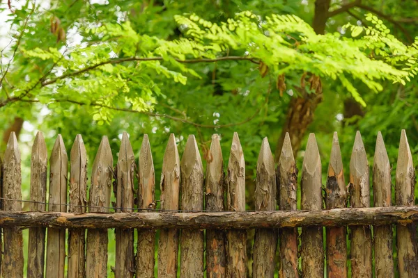 Wooden fence on the cottage. Fence with sharp peaks. Protective wooden structure from theft. Eco-friendly fence in the country